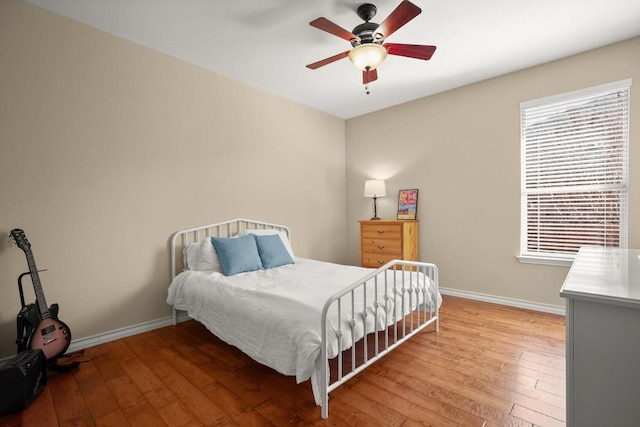 bedroom with a ceiling fan, baseboards, and hardwood / wood-style flooring