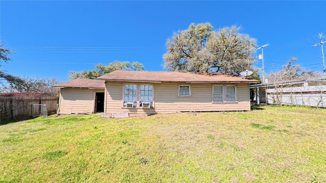 rear view of house featuring a lawn and a fenced backyard