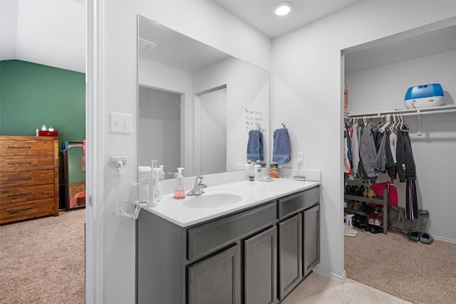 bathroom with vanity, lofted ceiling, a spacious closet, and tile patterned flooring