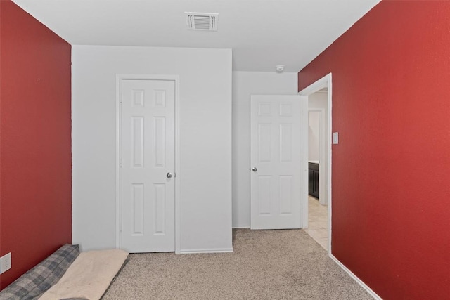 unfurnished bedroom featuring baseboards, visible vents, and light carpet