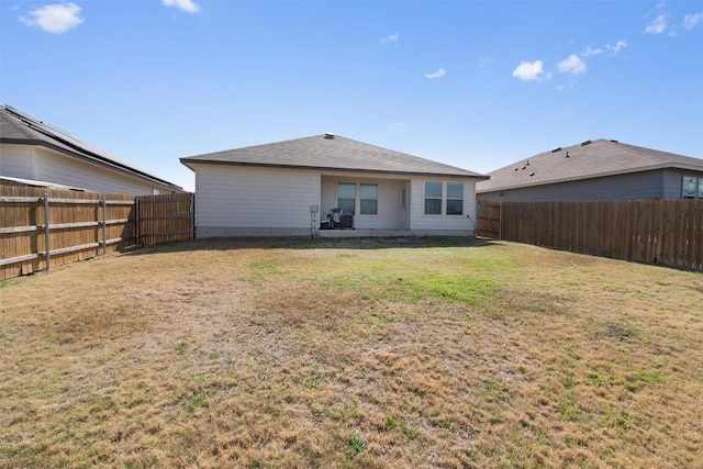 rear view of house with a fenced backyard and a yard