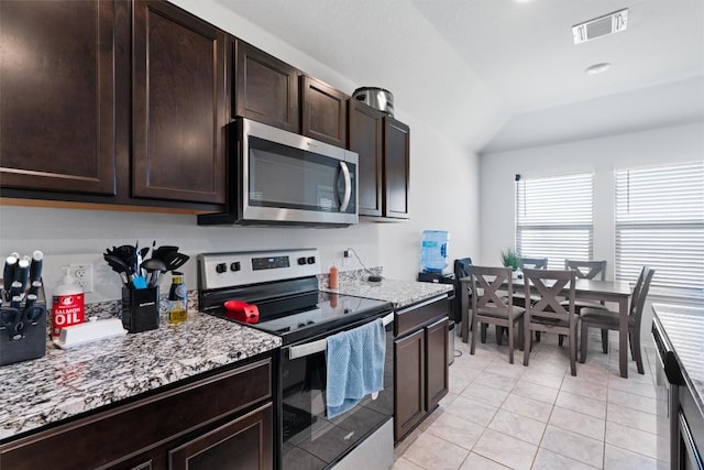 701 Taggart Trl, Jarrell, TX 76537 - kitchen with stainless steel appliances, light tile patterned flooring, dark brown cabinets, vaulted ceiling, and light stone countertops