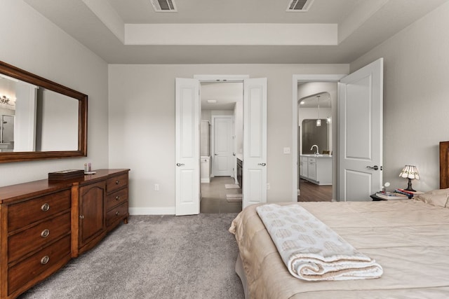 carpeted bedroom featuring visible vents, a raised ceiling, and baseboards