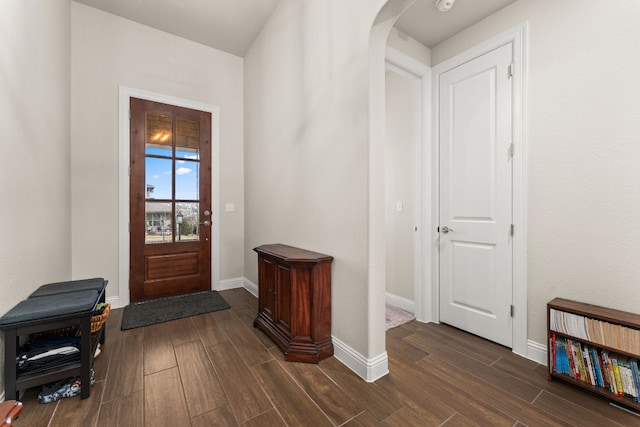 foyer featuring wood finish floors, baseboards, and arched walkways