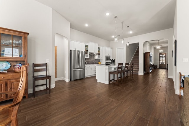 kitchen with stainless steel appliances, arched walkways, a breakfast bar, and dark wood-style floors