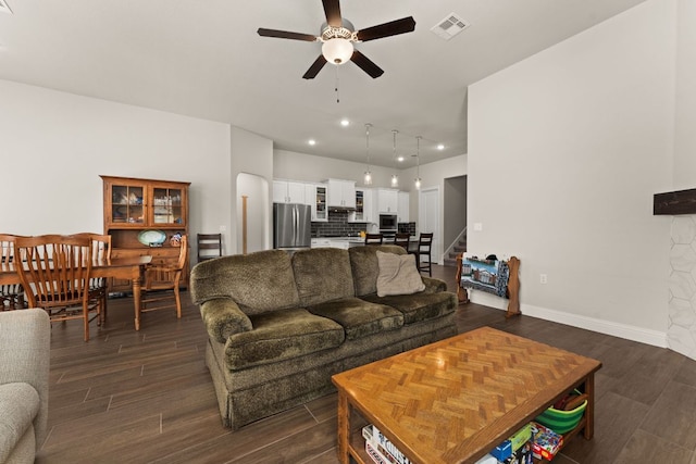 living room with dark wood finished floors, visible vents, stairs, and ceiling fan