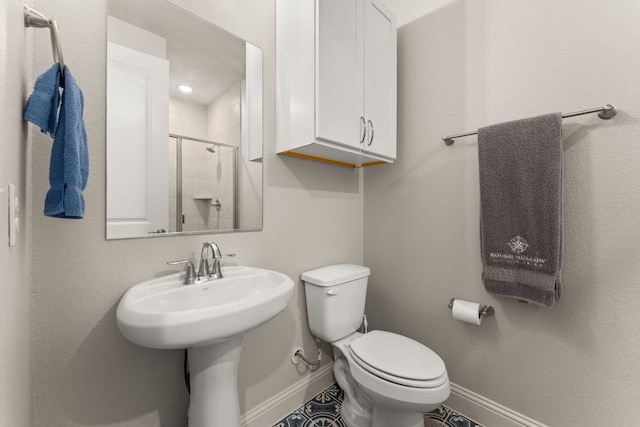 bathroom with a stall shower, toilet, and baseboards