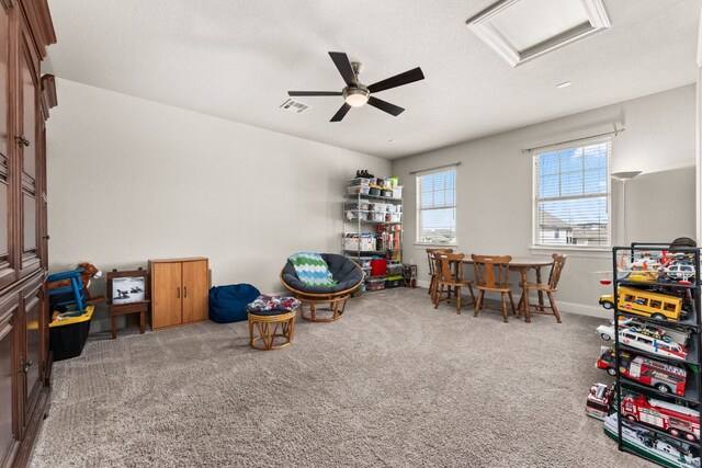 living area featuring visible vents, baseboards, ceiling fan, attic access, and carpet flooring