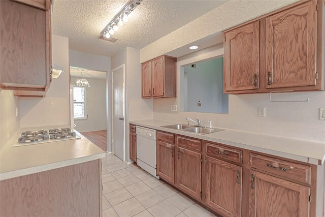 kitchen featuring light countertops, light tile patterned flooring, white appliances, a textured ceiling, and a sink