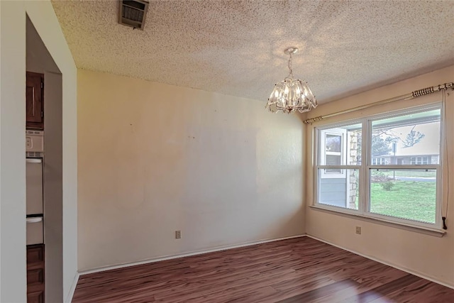 spare room featuring an inviting chandelier, wood finished floors, visible vents, and a textured ceiling