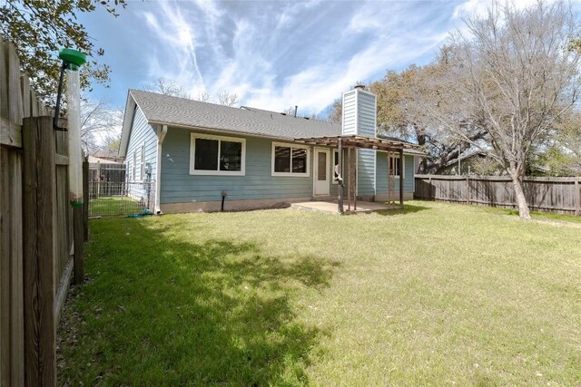 back of property with a patio area, a lawn, a fenced backyard, and a chimney