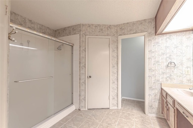 bathroom with a textured ceiling, a shower stall, and wallpapered walls