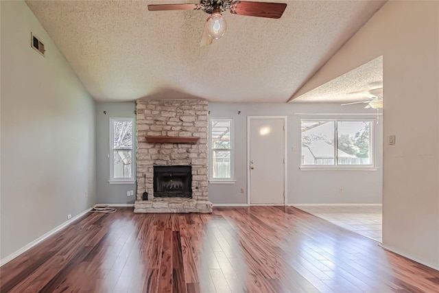 unfurnished living room featuring visible vents, vaulted ceiling, a fireplace, a ceiling fan, and wood-type flooring