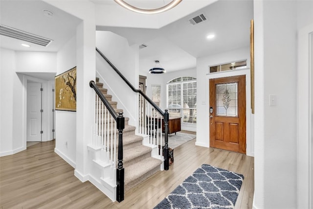 foyer entrance featuring stairs, light wood-style floors, and visible vents