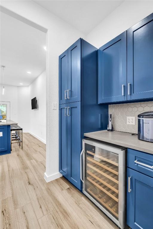 bar featuring decorative backsplash, wine cooler, baseboards, and light wood-style flooring