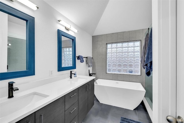 bathroom featuring tile patterned flooring, lofted ceiling, a soaking tub, and a sink