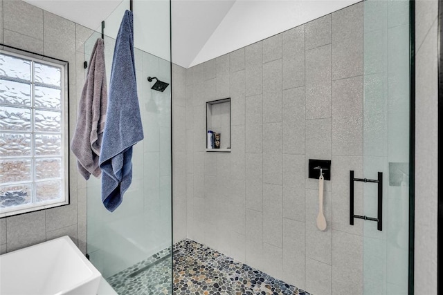 bathroom featuring a wealth of natural light, a soaking tub, a tile shower, and vaulted ceiling