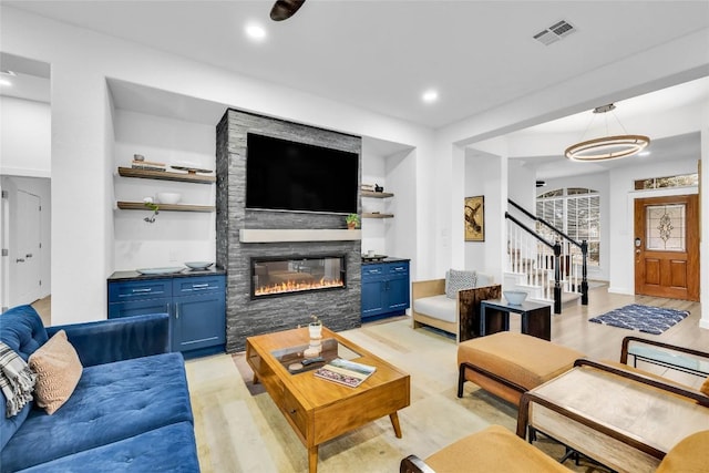 living area with light wood-type flooring, visible vents, recessed lighting, stairway, and a fireplace