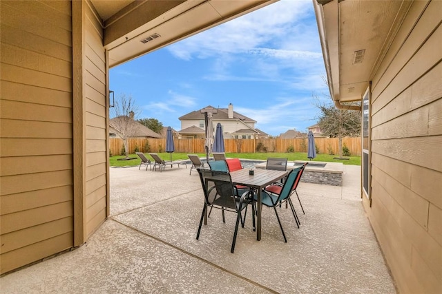 view of patio with outdoor dining area, a fenced backyard, and an outdoor fire pit