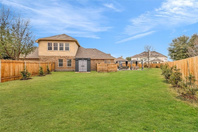 back of house with a patio, a fenced backyard, a yard, roof with shingles, and brick siding