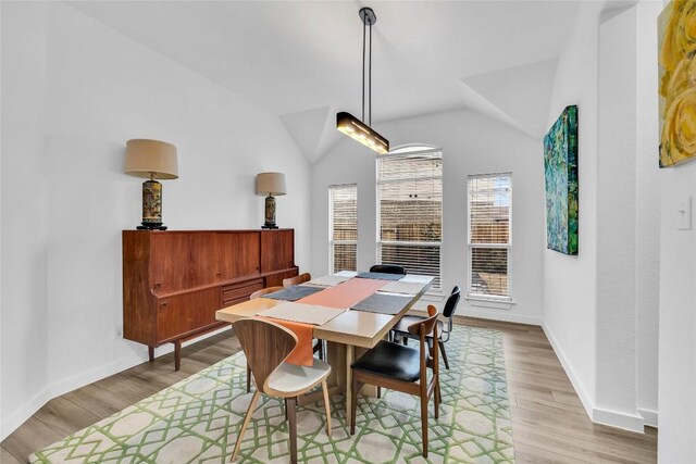dining space with light wood-style flooring, baseboards, and lofted ceiling