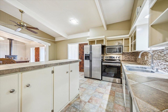 kitchen featuring a sink, open shelves, tasteful backsplash, stainless steel appliances, and a wood stove