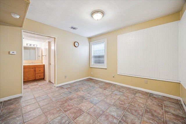 unfurnished bedroom with baseboards, visible vents, and a sink