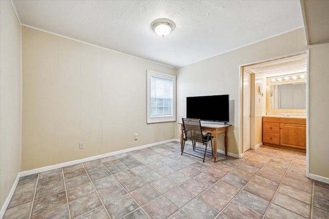 interior space featuring a textured ceiling, baseboards, and ornamental molding