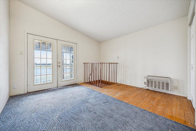 spare room featuring vaulted ceiling, wood finished floors, french doors, and a textured ceiling