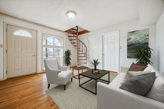 living area with stairway, light wood-type flooring, and a textured ceiling