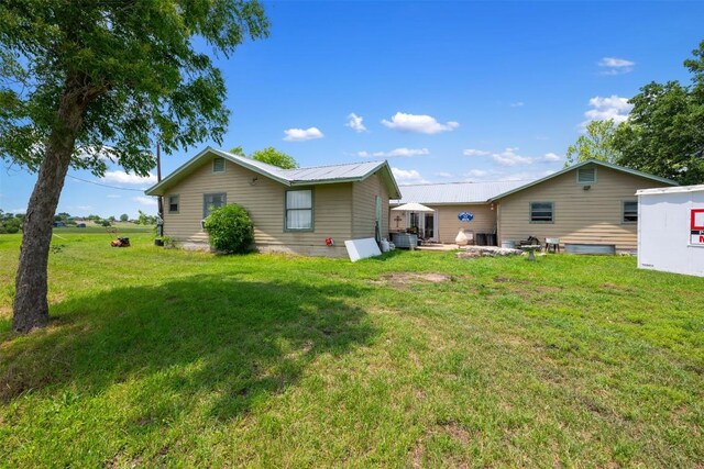 rear view of property featuring a yard and metal roof