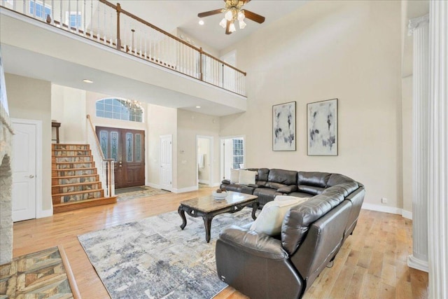 living room with baseboards, stairs, a ceiling fan, and wood finished floors