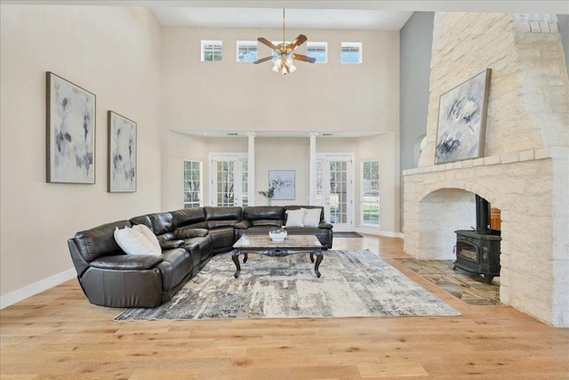 living room with plenty of natural light, a wood stove, ceiling fan, and wood finished floors