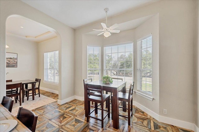 dining room featuring baseboards, arched walkways, and ceiling fan