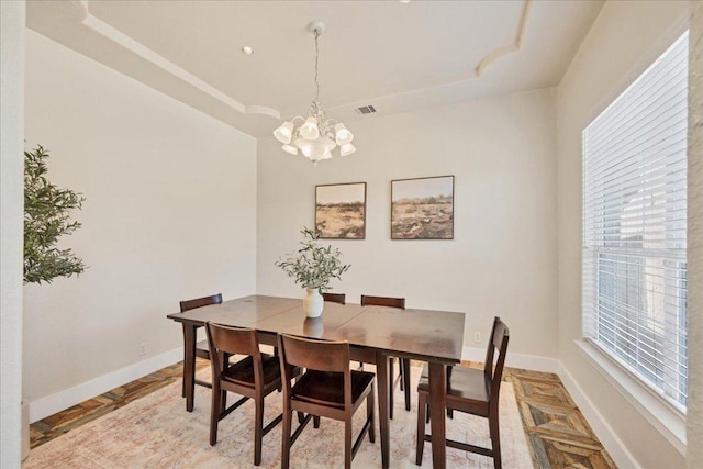 dining area with a tray ceiling, baseboards, a notable chandelier, and visible vents