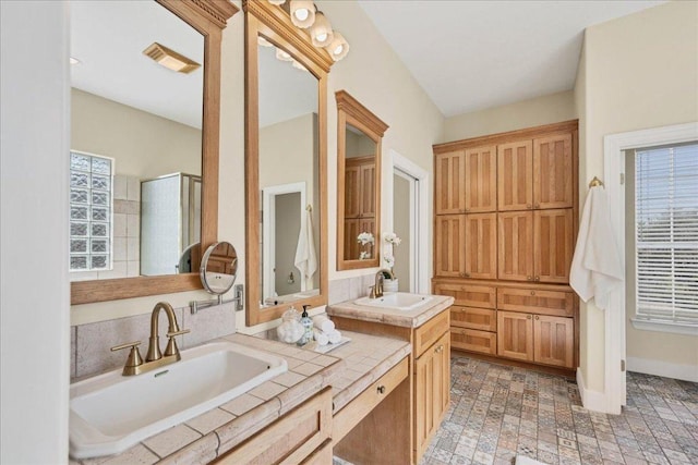 full bath with double vanity, baseboards, visible vents, and a sink