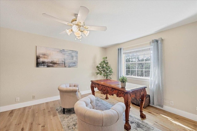 office space with baseboards, light wood-style flooring, and a ceiling fan