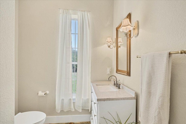 bathroom featuring baseboards, toilet, and vanity