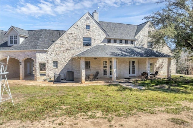 rear view of house with stone siding, a patio, central AC unit, and a chimney