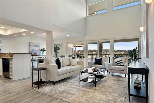 living area featuring recessed lighting, a healthy amount of sunlight, light wood-type flooring, and a towering ceiling