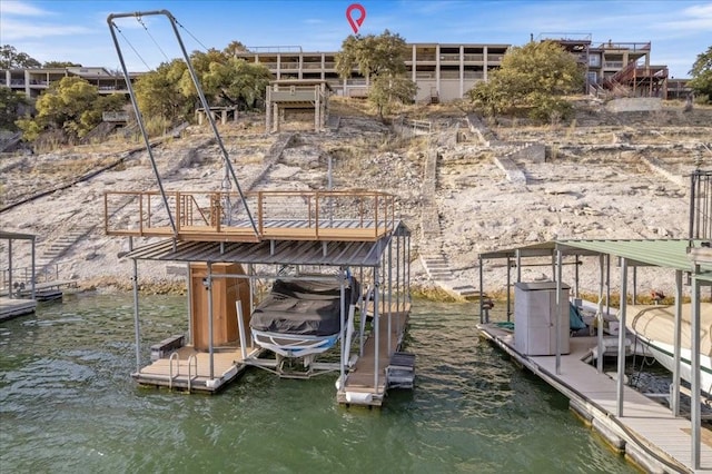 dock area with a water view, boat lift, and stairs