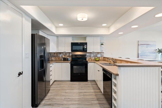 kitchen with light wood finished floors, open shelves, a sink, black appliances, and tasteful backsplash