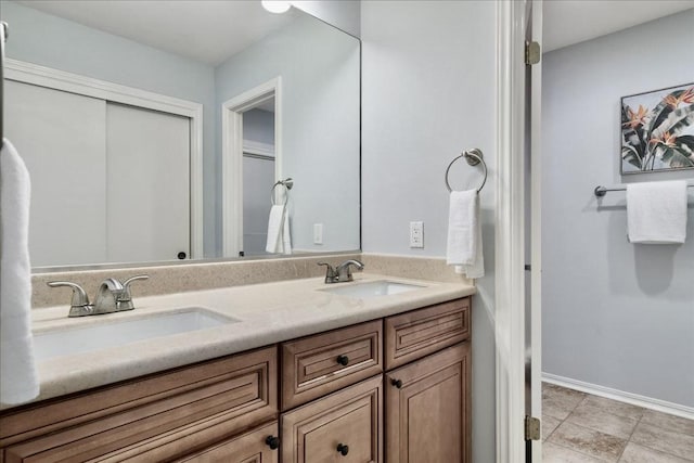 full bath featuring a sink, baseboards, and double vanity