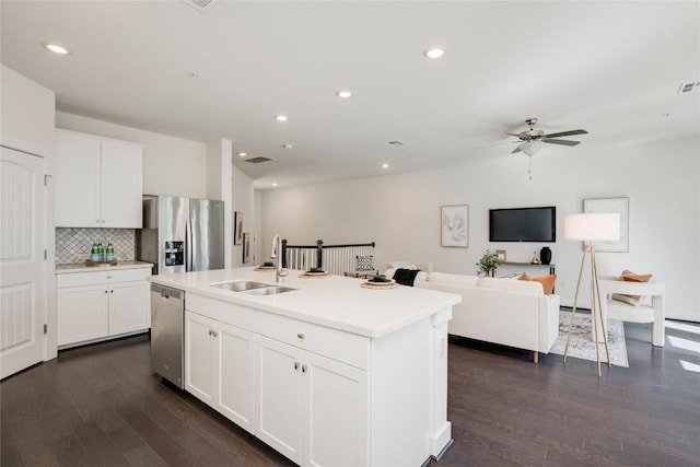 kitchen with decorative backsplash, dark wood-style floors, stainless steel appliances, a ceiling fan, and a sink