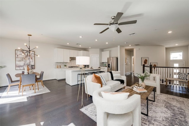 living room featuring visible vents, baseboards, recessed lighting, dark wood-type flooring, and ceiling fan with notable chandelier