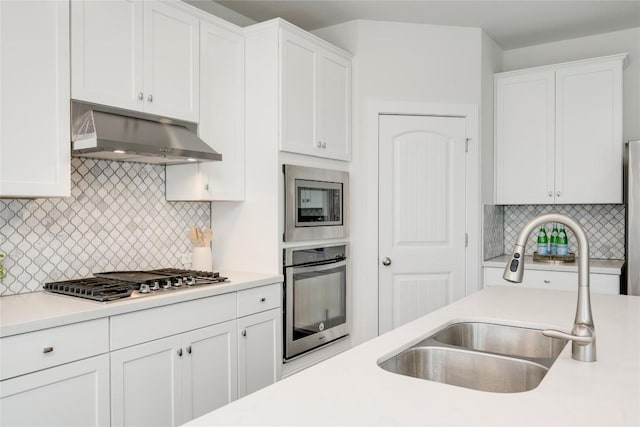 kitchen featuring under cabinet range hood, light countertops, appliances with stainless steel finishes, white cabinetry, and a sink