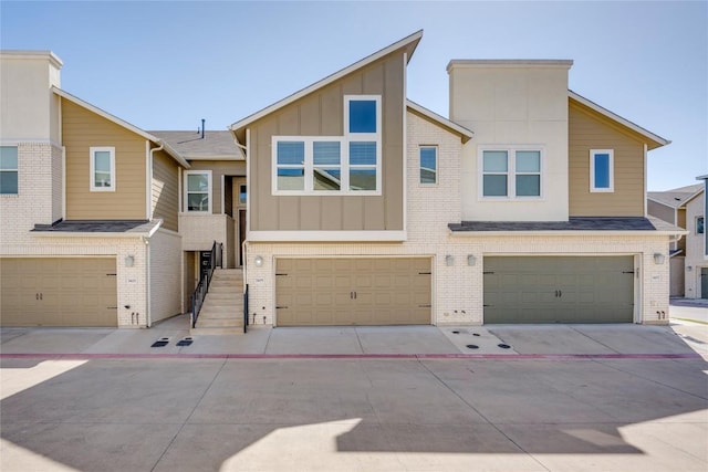 multi unit property with stairway, a garage, brick siding, and board and batten siding