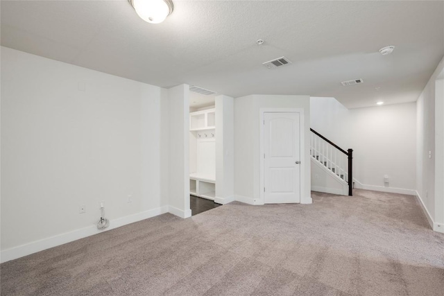 basement with visible vents, carpet flooring, and stairway