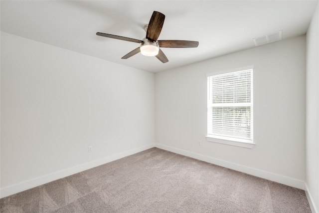 carpeted spare room featuring visible vents, baseboards, and ceiling fan