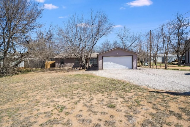 exterior space with an attached garage, gravel driveway, and fence